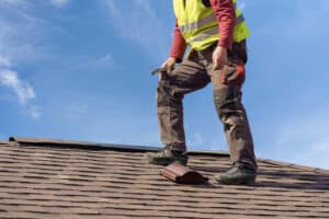 man inspecting roof shingles for signs of wear and damage
